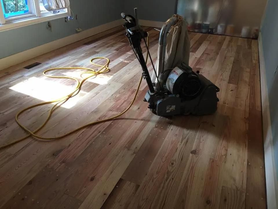 Vacuum cleaner on a wooden floor in a sunlit room, with a yellow cord near the window.
