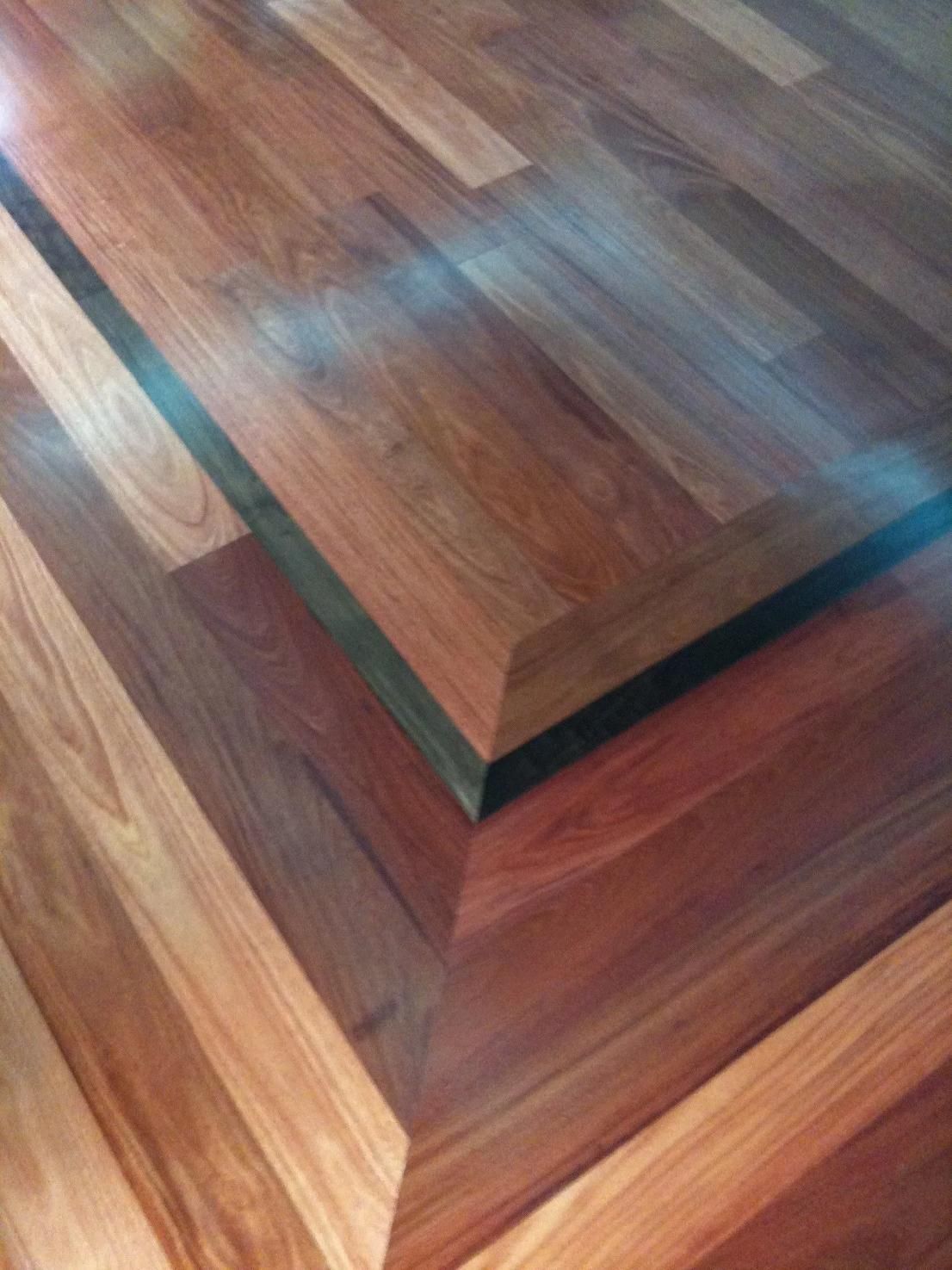 Close-up of a glossy wood staircase with reddish-brown and dark trim patterns