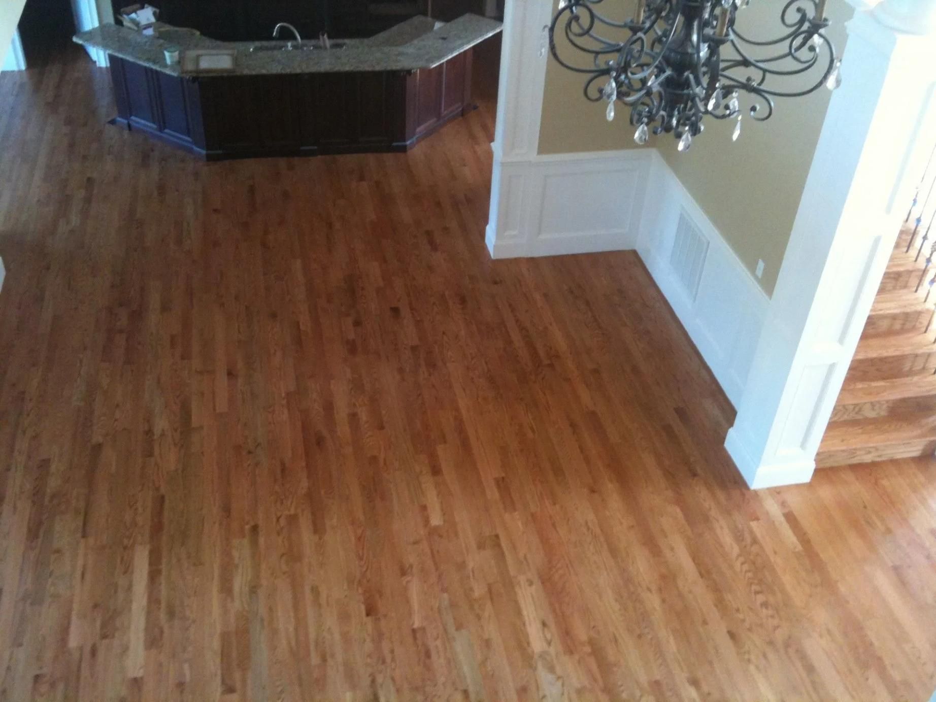 Empty hardwood living room with a dark fireplace and chandelier.