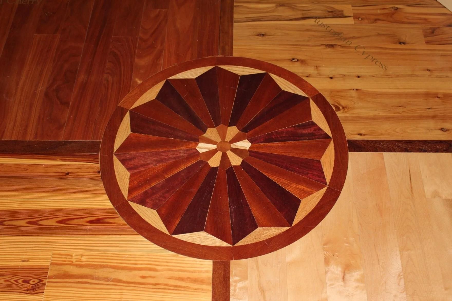 Wooden floor inlay with a circular sunburst medallion in brown and tan tones