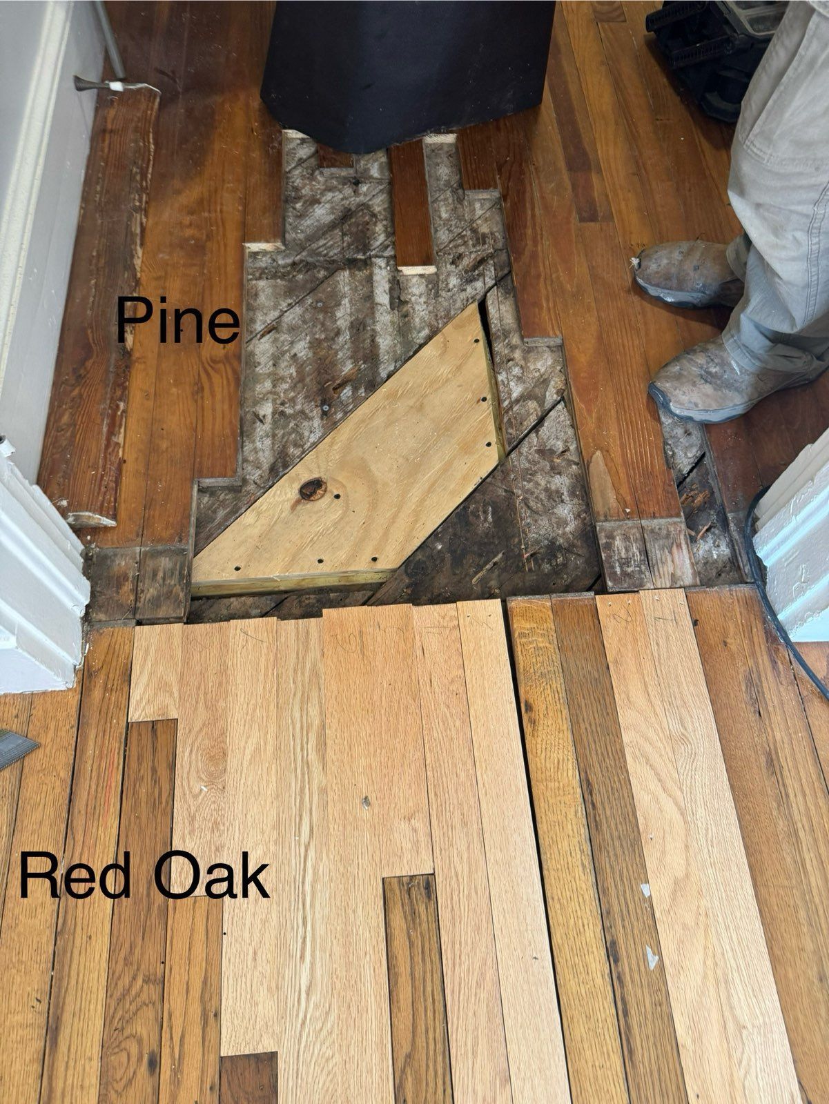 Floor repair showing mixed pine and red oak boards with a damaged section and exposed subfloor.