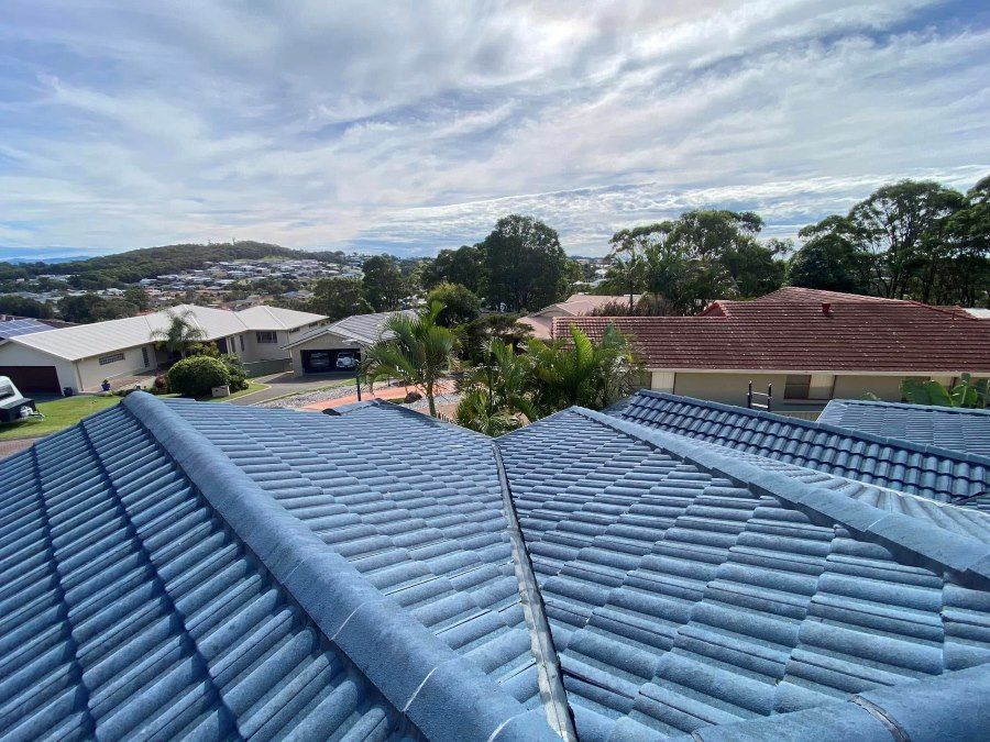 A blue tiled roof of a house with a view of a city.