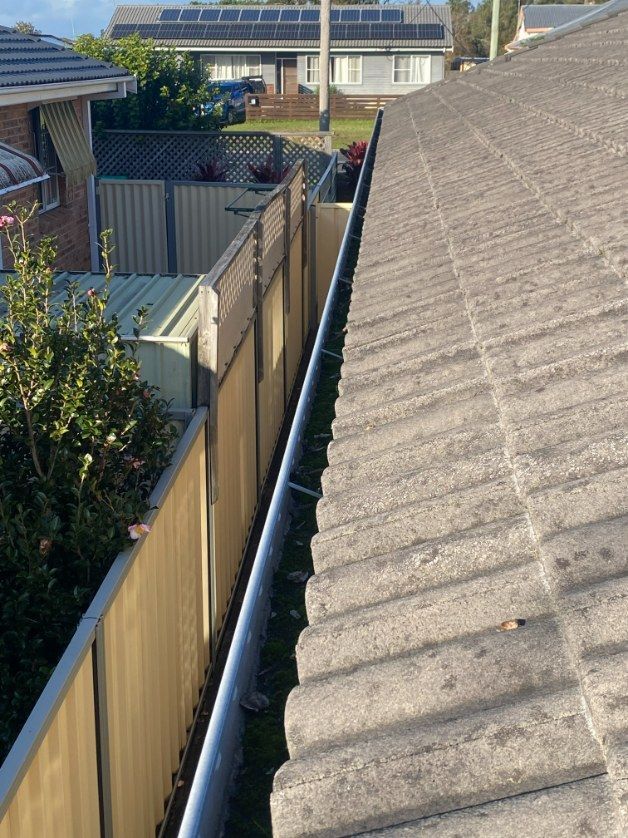 A Close Up Of A Gutter On A Roof With Trees In The Background — The Guttering Cleaning Man in Forster, NSW