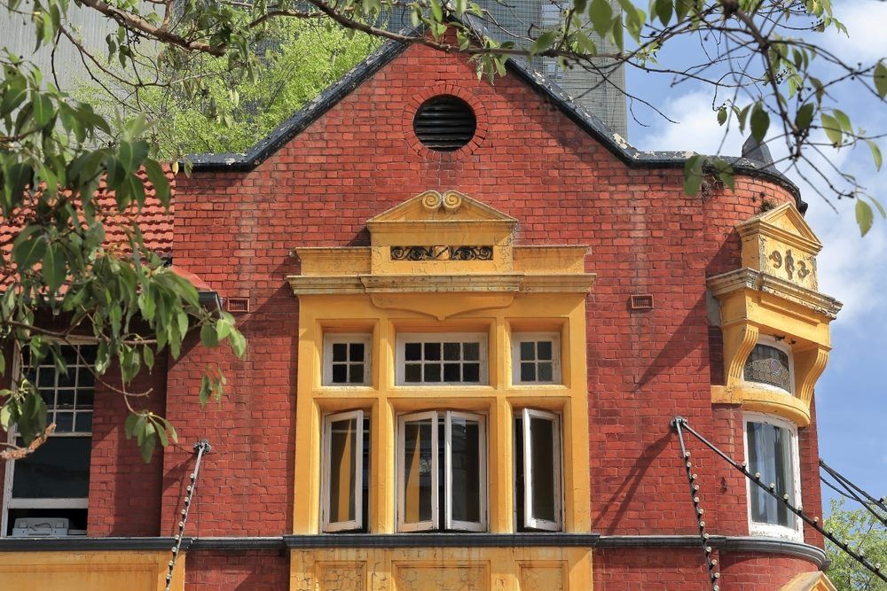 A Red Brick Building With Yellow Trim And Windows — The Guttering Cleaning Man in Old Bar, NSW