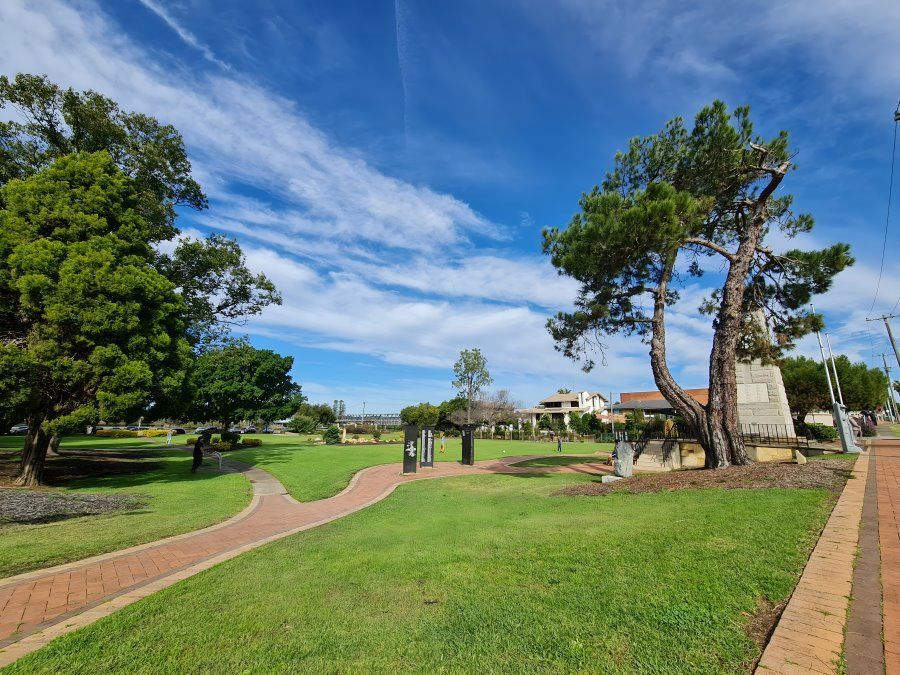 A park with a brick walkway and trees on a sunny day — The Guttering Cleaning Man in Taree, NSW