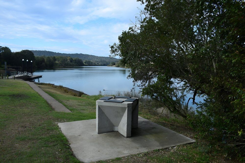 A Concrete Table Is Sitting In The Grass Next To A Lake — The Guttering Cleaning Man in Wingham, NSW