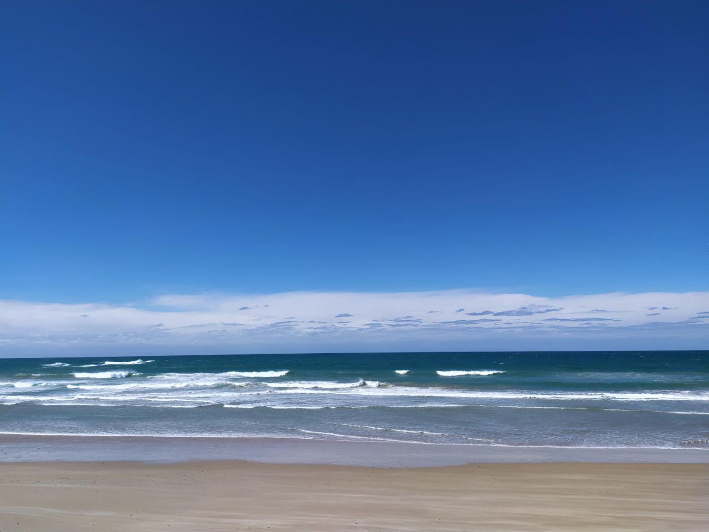 A Beach With A Blue Sky And Waves Coming In — The Guttering Cleaning Man in Old Bar, NSW