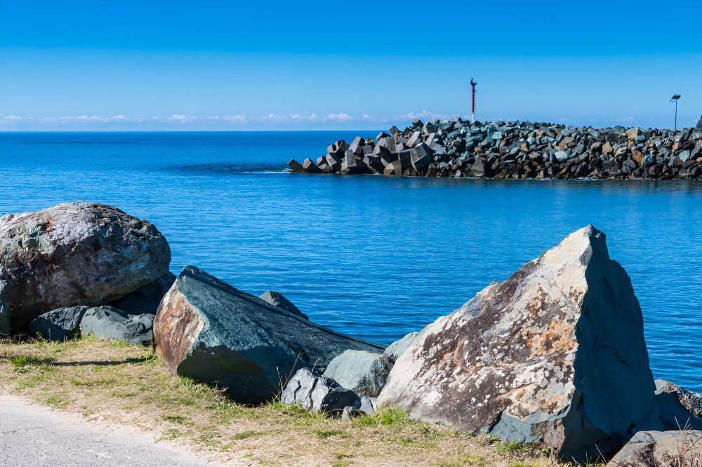 A Large Rock Sitting On The Shore Of A Body Of Water — The Guttering Cleaning Man in Tuncurry, NSW