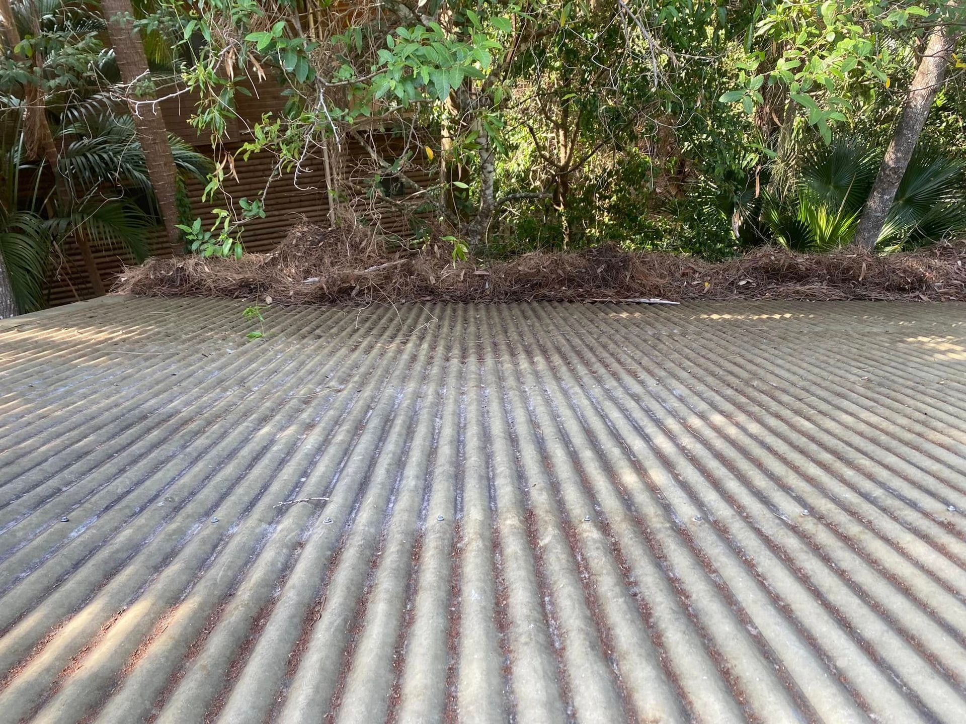 A Man Is Using A High Pressure Washer To Clean A Patio — The Guttering Cleaning Man in Nabiac, NSW