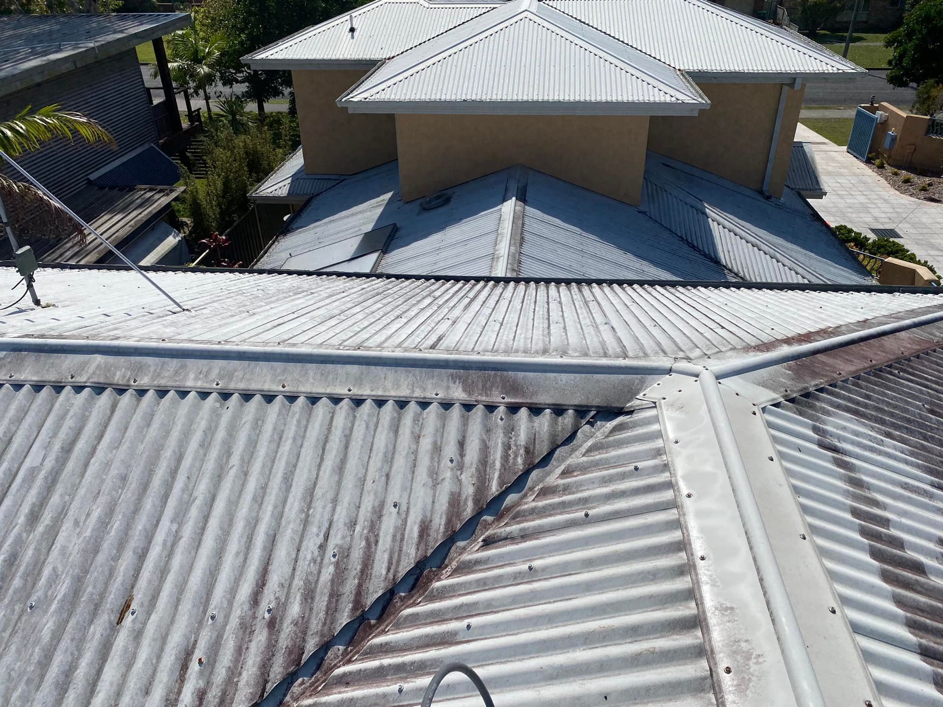 A Man Is Using A High Pressure Washer To Clean A Brick Driveway — The Guttering Cleaning Man in Forster, NSW