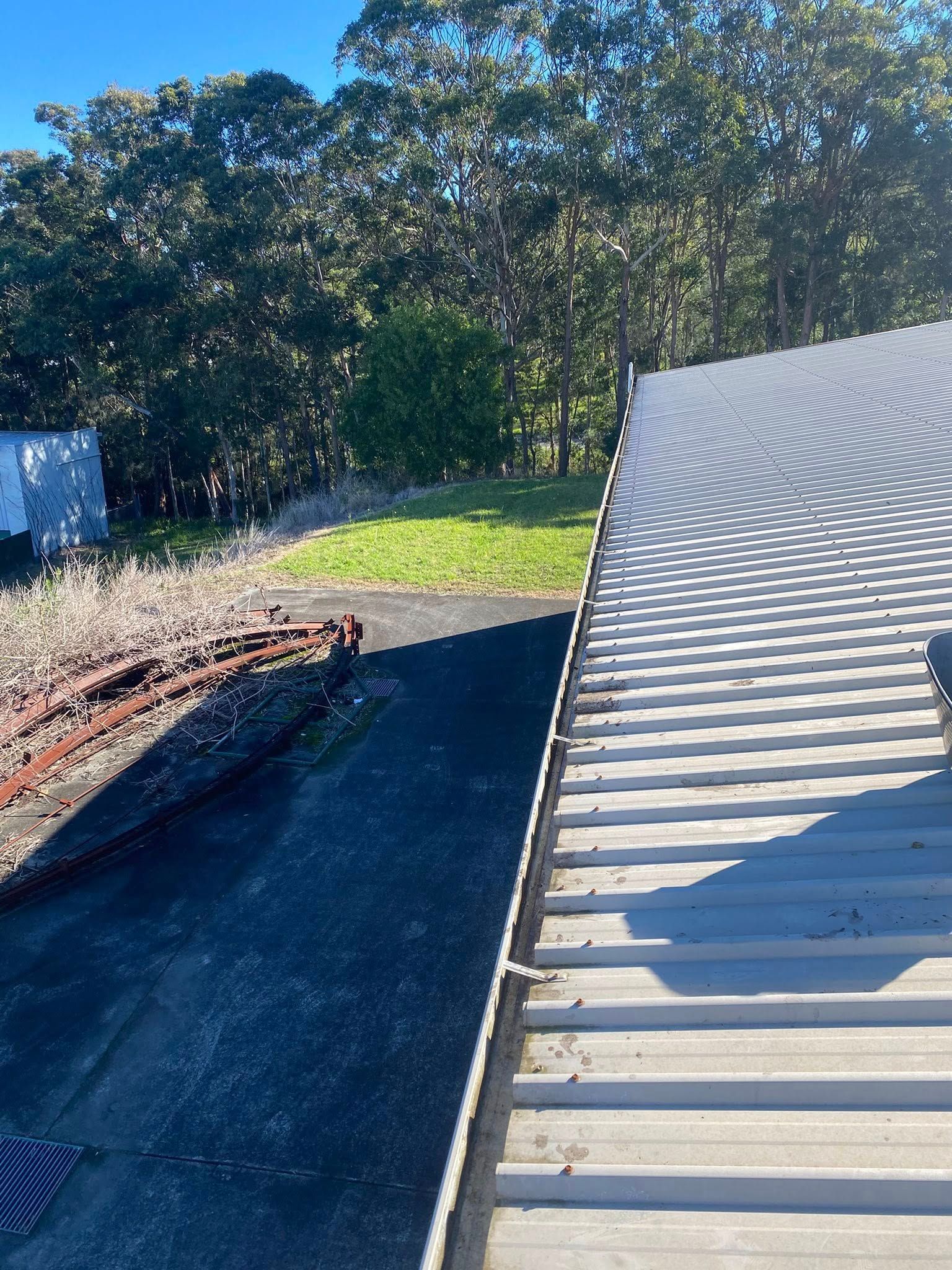 A Roof With A Gutter On It And Trees In The Background — The Guttering Cleaning Man in Forster, NSW