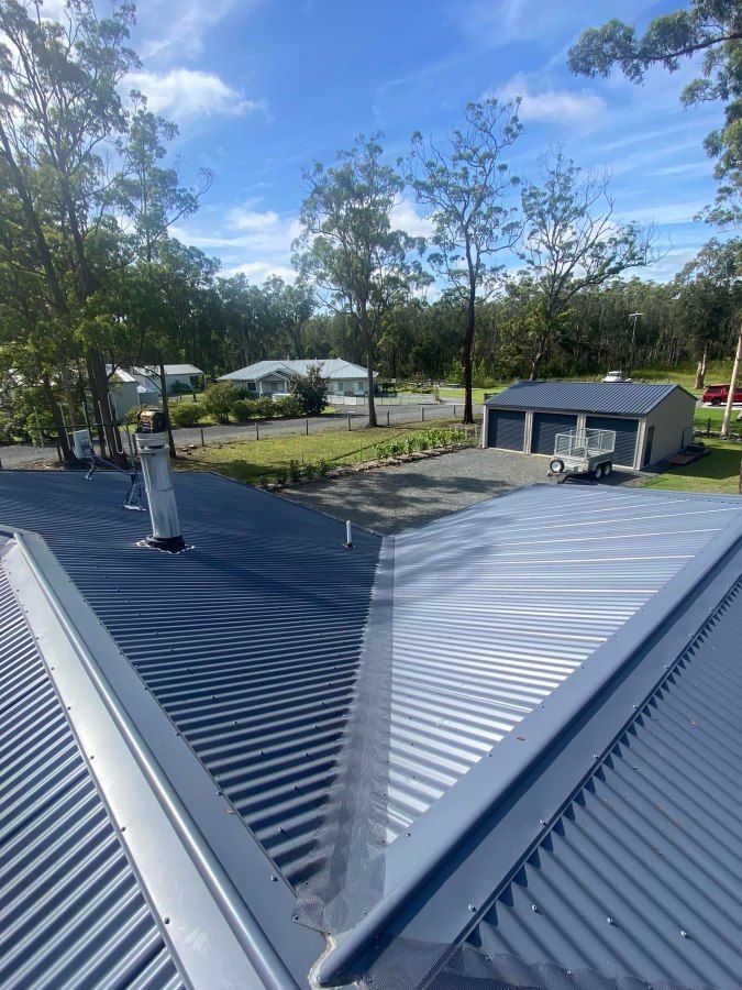 A Roof With A Chimney On It And A Garage In The Background — The Guttering Cleaning Man in Wingham, NSW