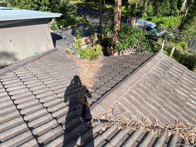 A Shadow Of A Person Is Cast On The Roof Of A House — The Guttering Cleaning Man in Harrington, NSW