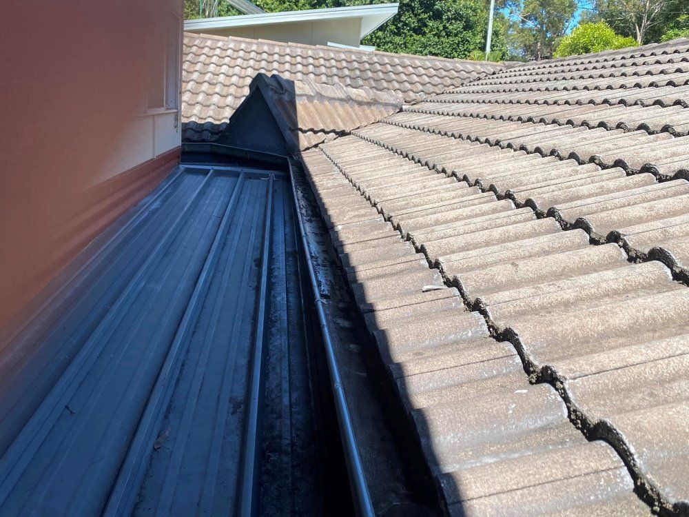 A close up of a gutter on a tiled roof.