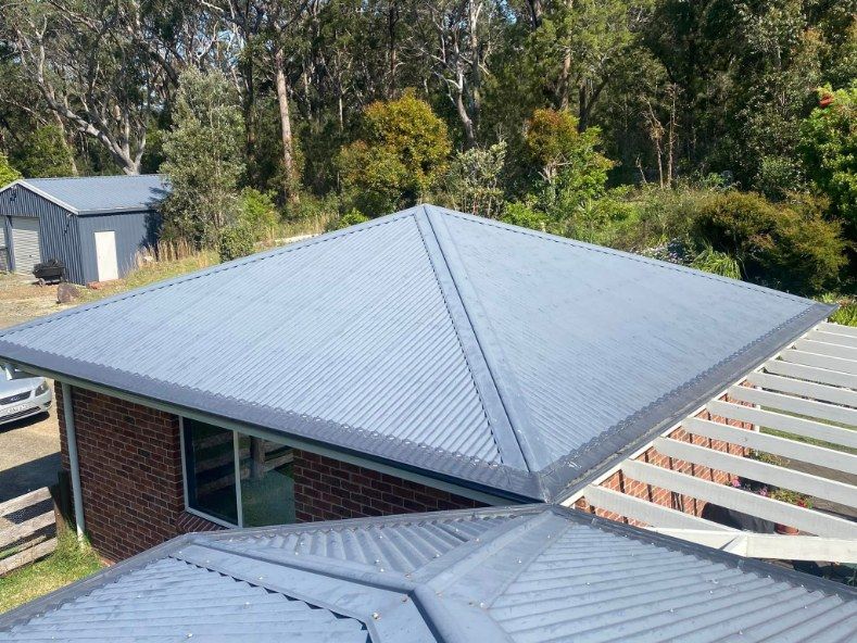 An Aerial View Of A House With A Blue Roof And Trees In The Background — The Guttering Cleaning Man in Forster, NSW