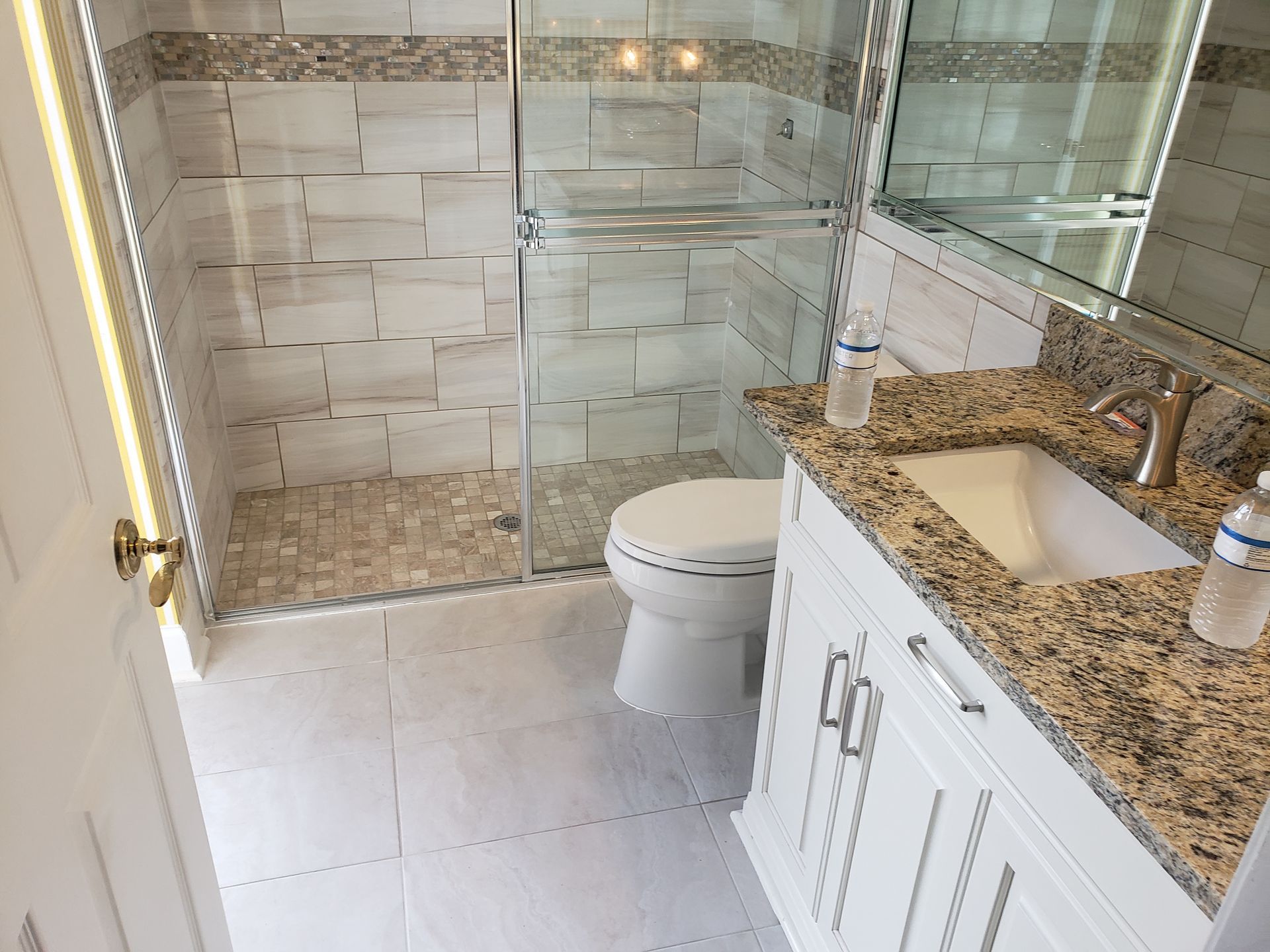 Modern bathroom with glass shower, white toilet, and granite vanity countertop