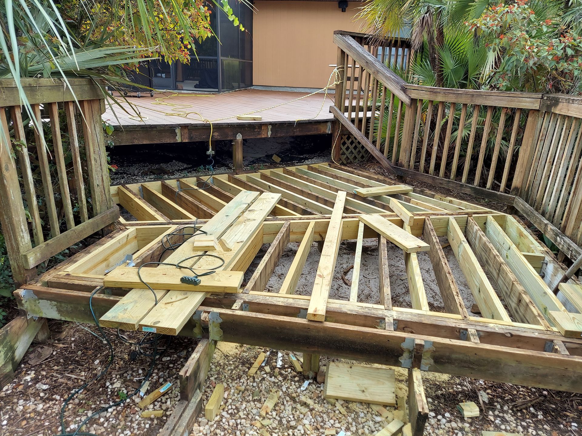 Damaged wooden deck with broken boards and scattered lumber in a backyard