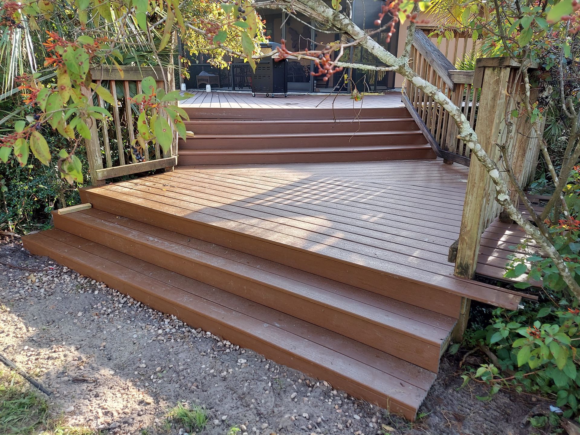 Wooden outdoor staircase with handrails and a small ramp amid greenery