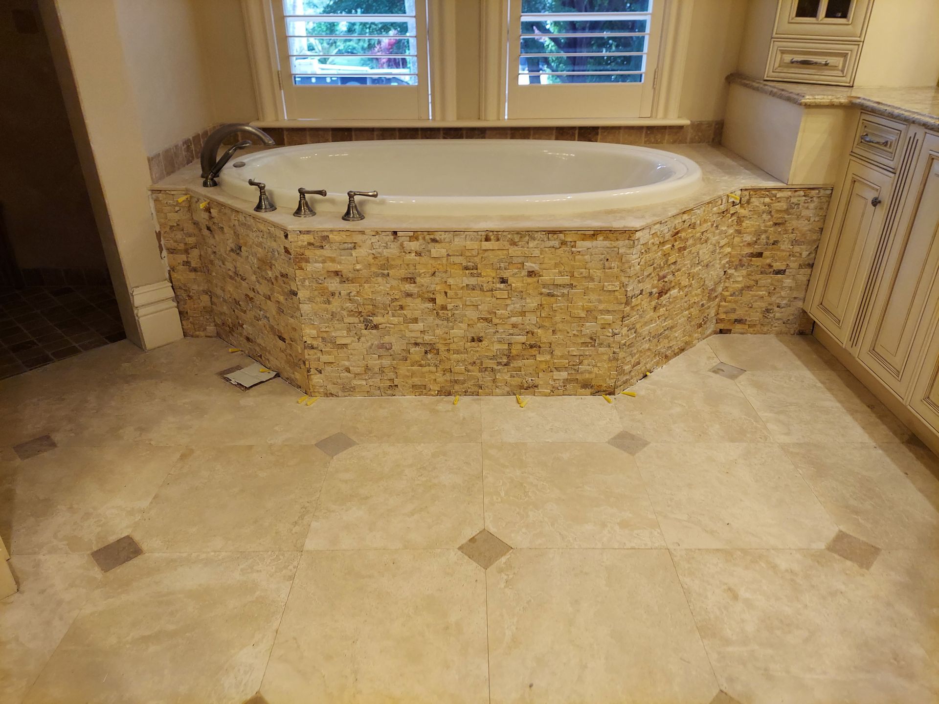 Spa-like bathroom with a stone-tiled soaking tub and beige tiled floor
