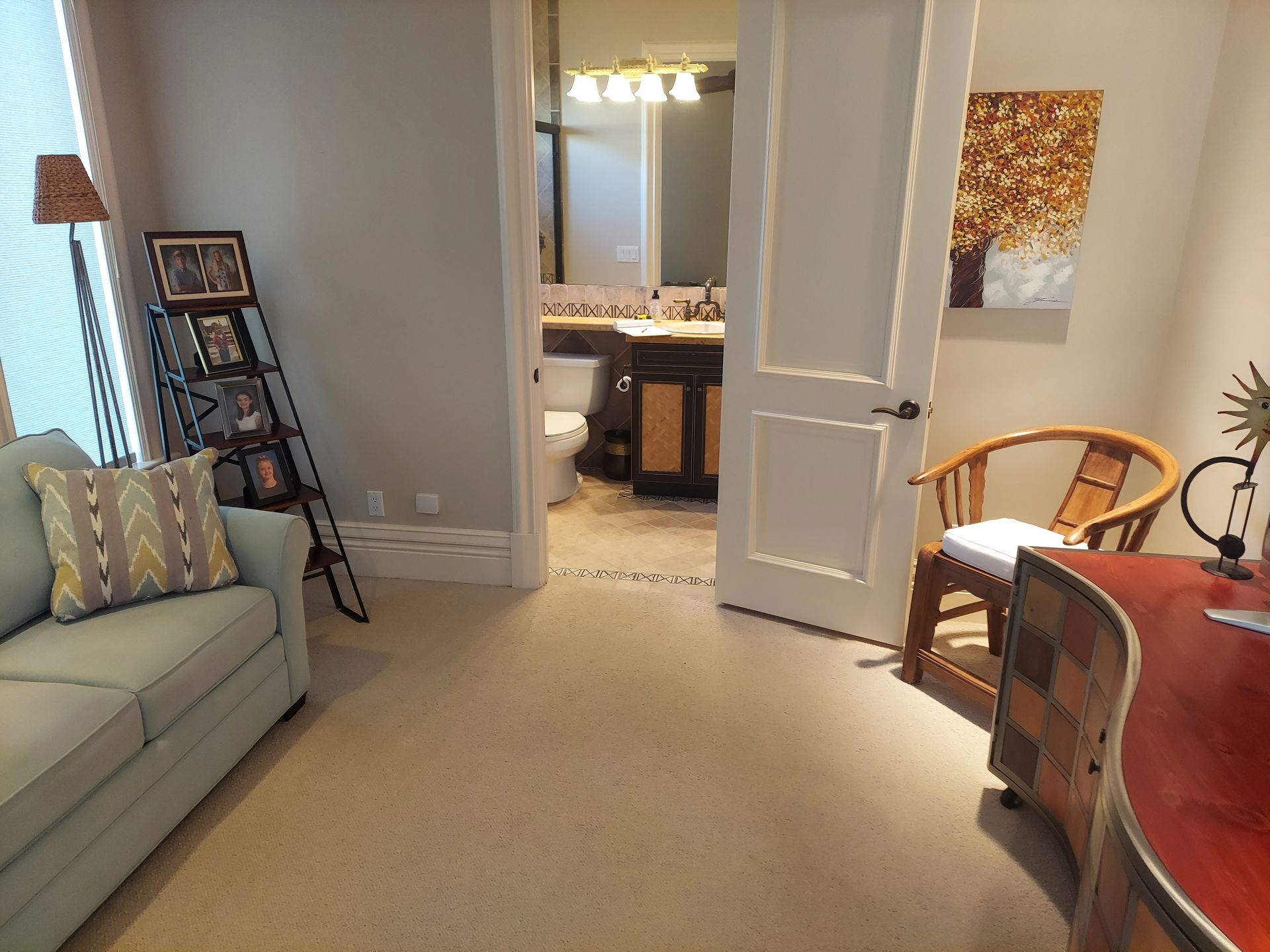 Living room with sofa, chair, piano, and open door to a lit bathroom