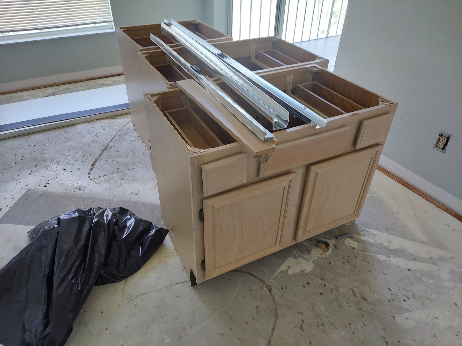 Kitchen cabinet with drawers and metal rails on a floor in a room under renovation.
