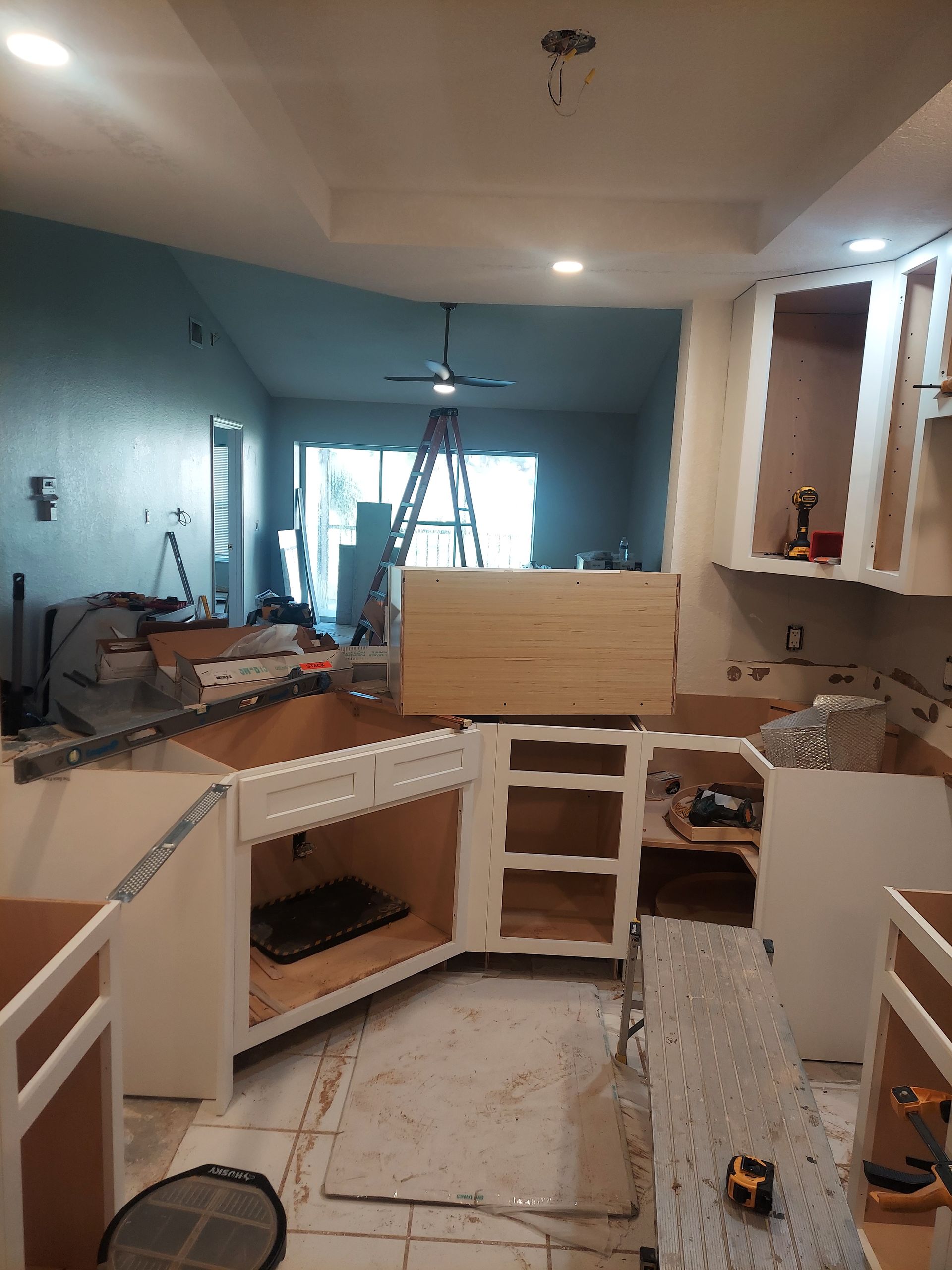 Partially built kitchen with white cabinets, wood countertops, and tools on the floor