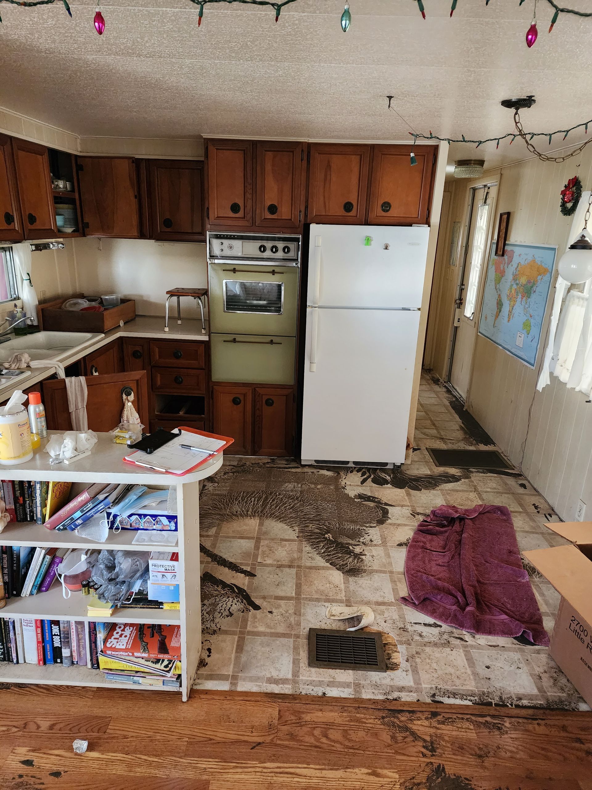 Small cluttered kitchen with wood cabinets, white fridge, stove, patterned floor, and a rug near the counter.