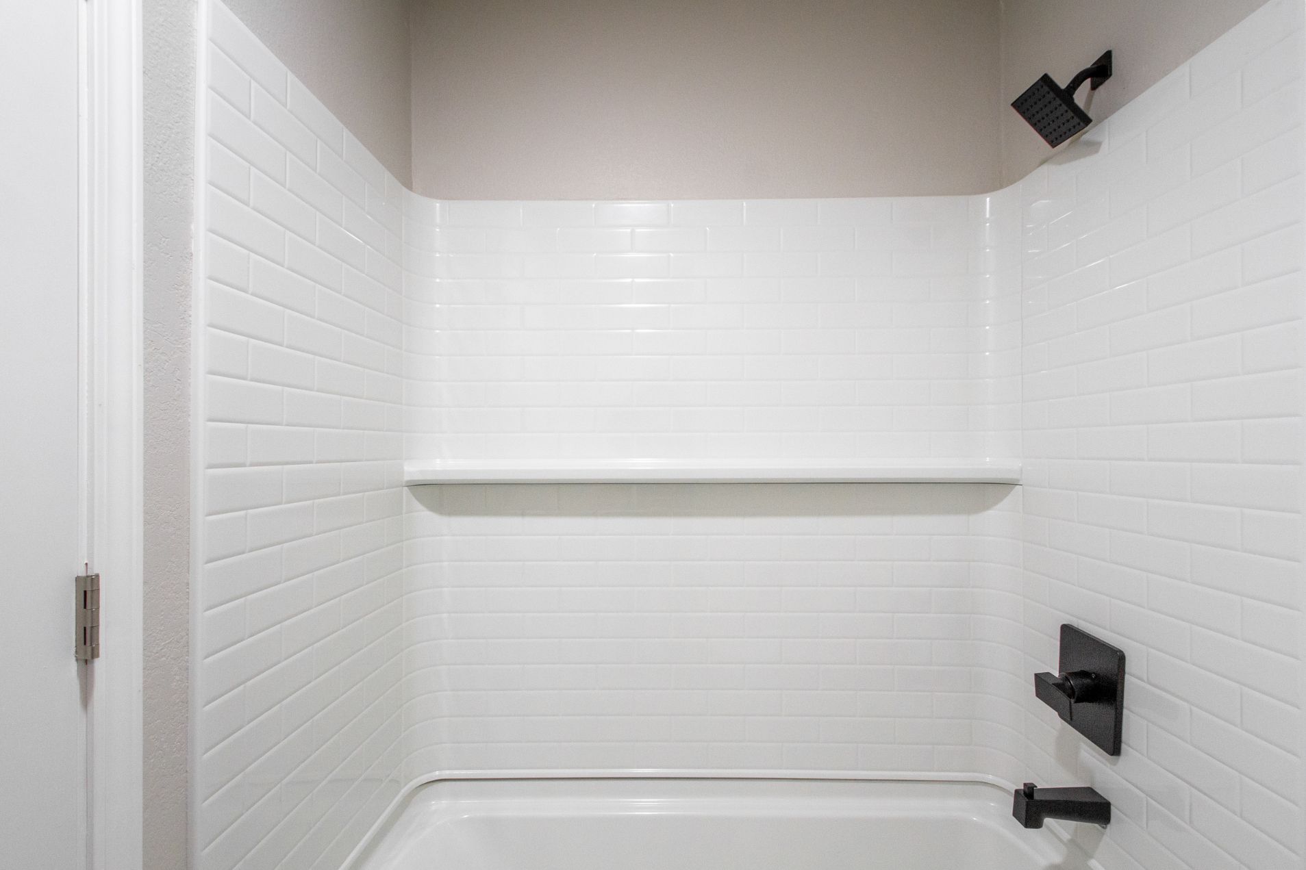 White tiled shower with black fixtures.