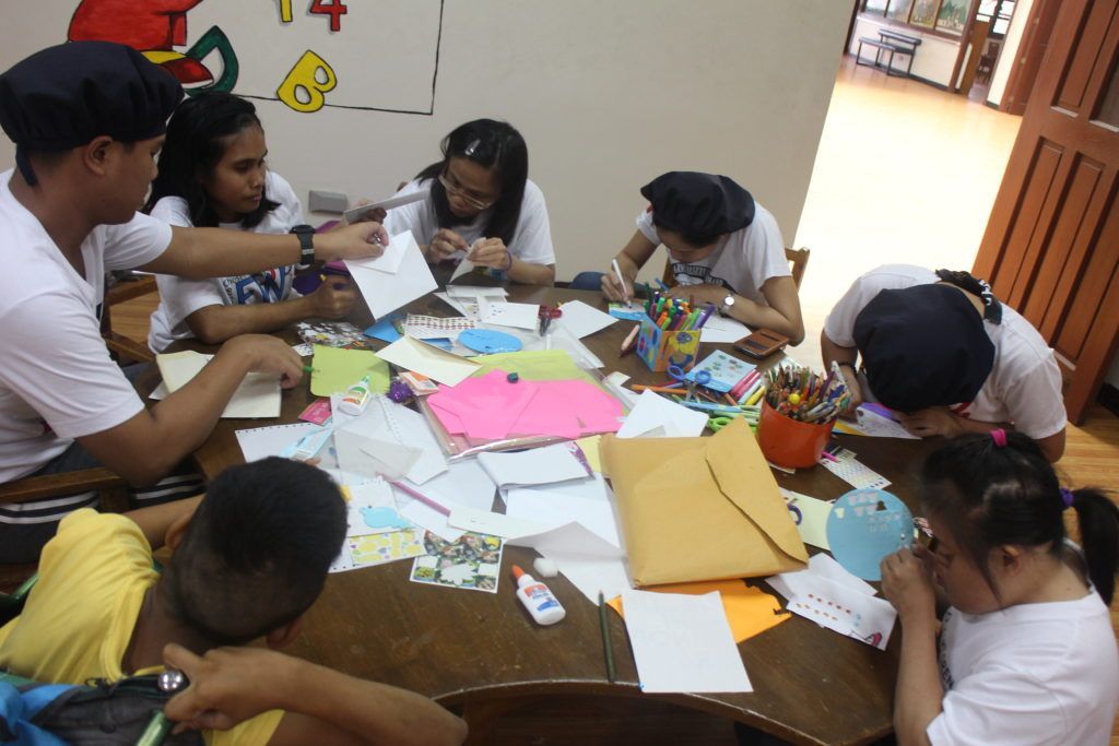 A group of children are sitting around a table with papers and pencils