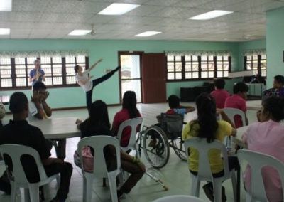A group of people are sitting around a table watching a ballerina perform