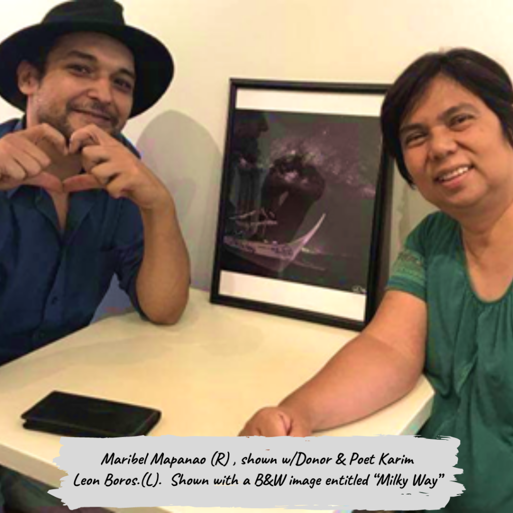 A man and a woman are sitting at a table in front of a framed picture.