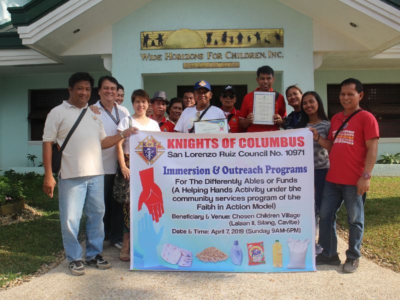 A group of people standing in front of a sign that says knights of columbus