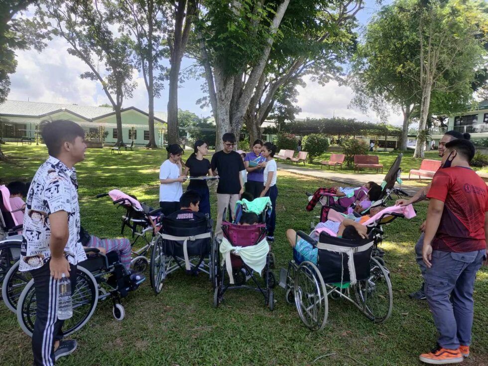 A group of people in wheelchairs are standing in a park.