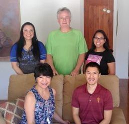 A group of people are posing for a picture while sitting on a couch.