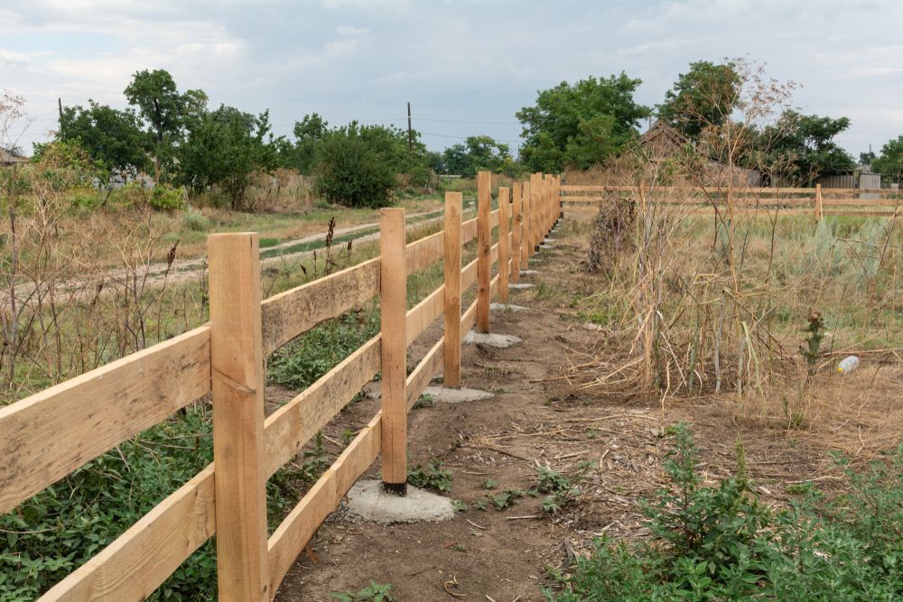 A Wooden Fence is Sitting in the Middle of a Field — Perry's Timber & Fencing In Albion Park, NSW