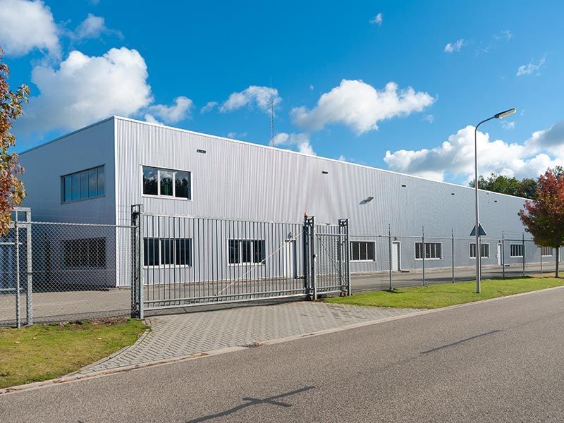 A Large White Building With A Fence Around It — Perry's Timber & Fencing In Dapto, NSW