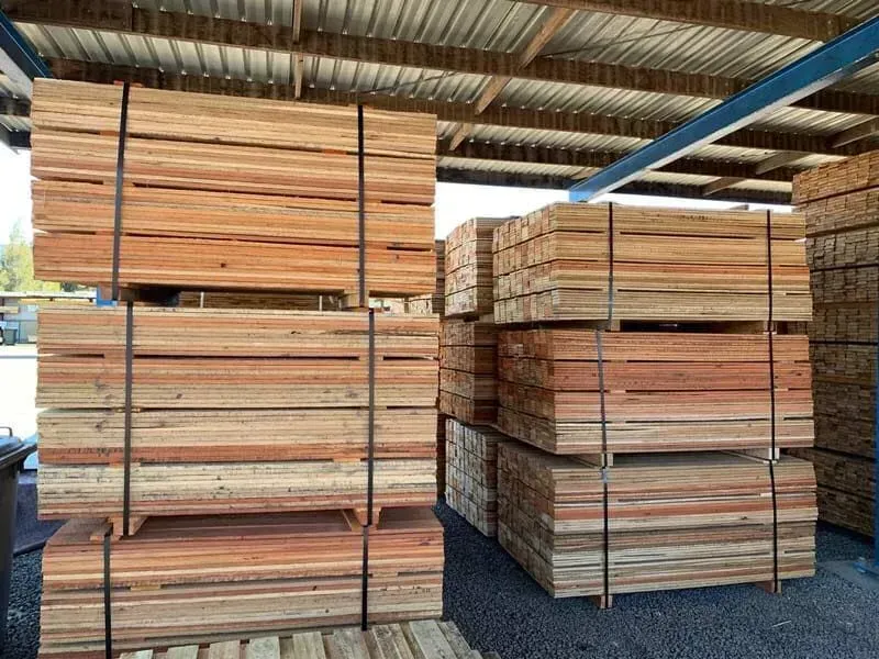 A Bunch Of Wooden Pallets Are Stacked On Top Of Each Other Under A Roof — Perry's Timber & Fencing In Dapto, NSW
