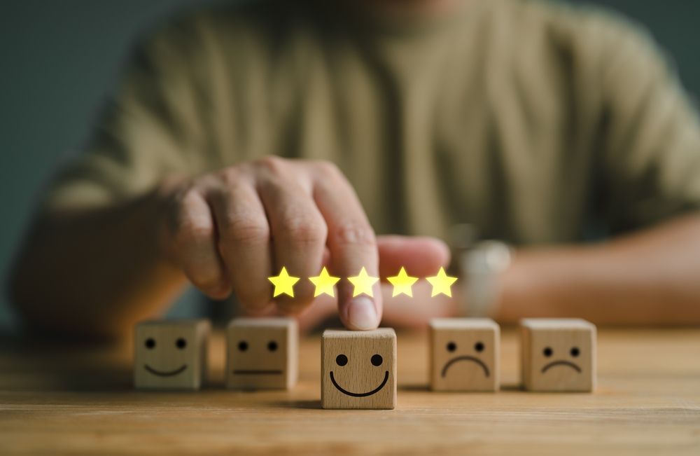 Person placing glowing stars above a wooden block with a smiley face; other blocks have neutral and sad faces.