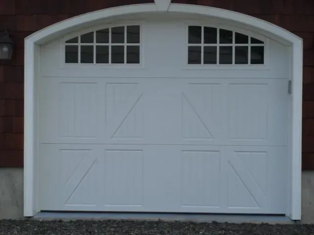 White arched double garage door with small window panes at the top