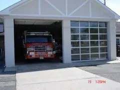 Fire truck parked inside a garage bay with a glass door, facing forward.
