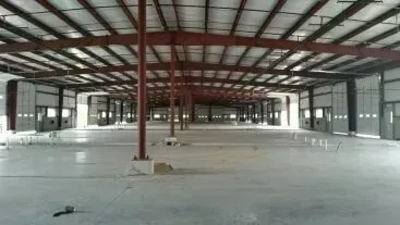 Empty industrial warehouse with steel beams and concrete floor under construction
