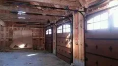 Empty wooden garage interior with large sliding doors and sunlight through windows