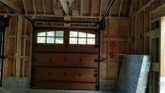 Interior of a garage under construction with a closed wooden door and exposed framing.