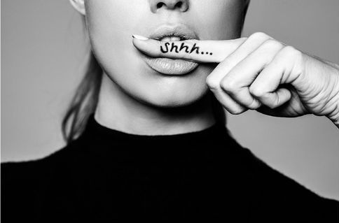 A black and white photo of a woman covering her mouth with her finger ..