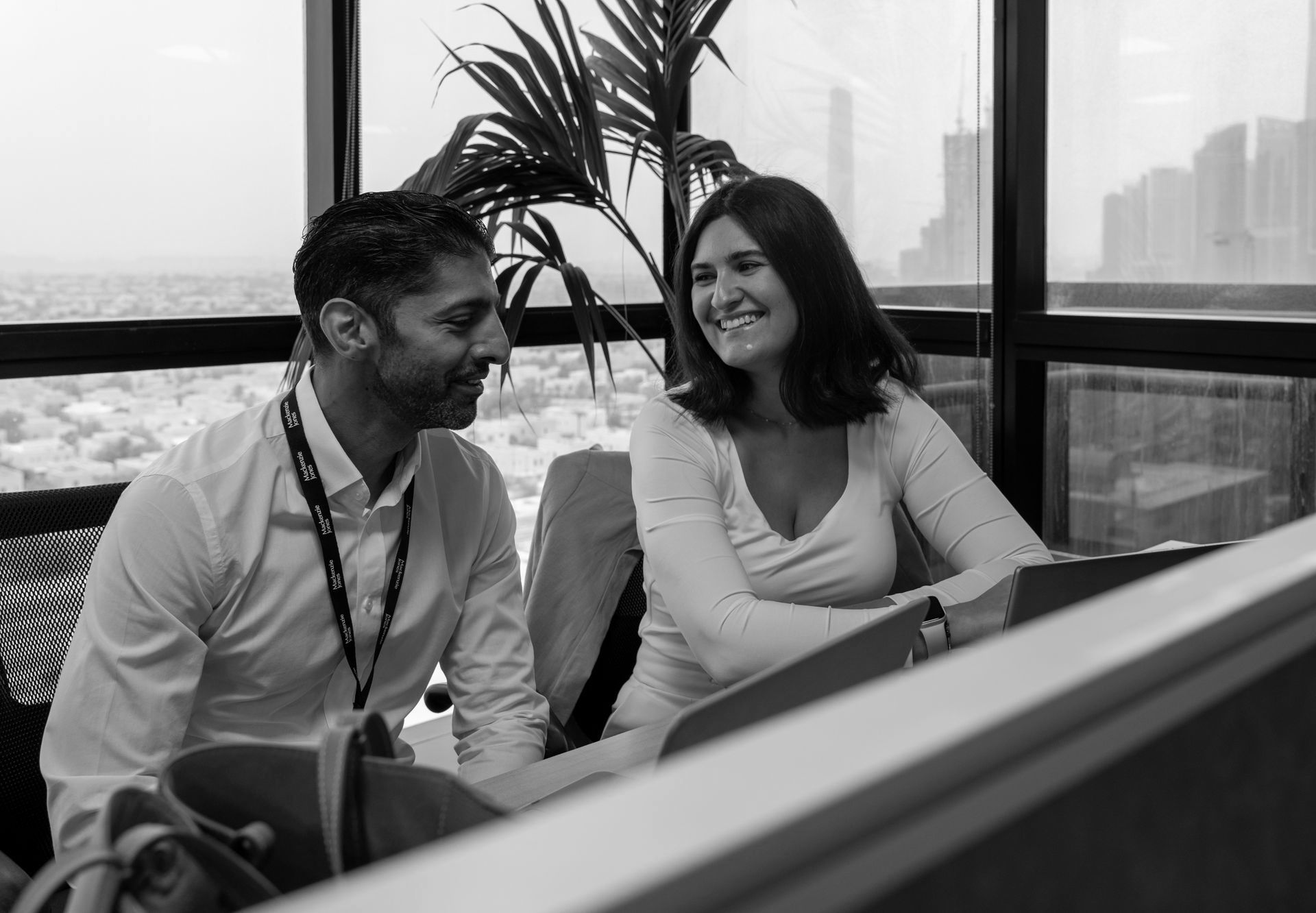 A man and a woman are sitting at a table looking at a tablet.