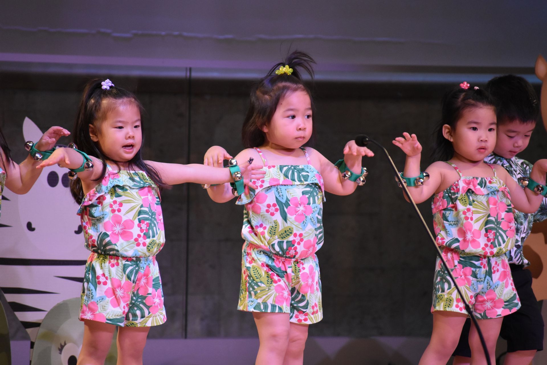 Young children in floral outfits performing on stage.