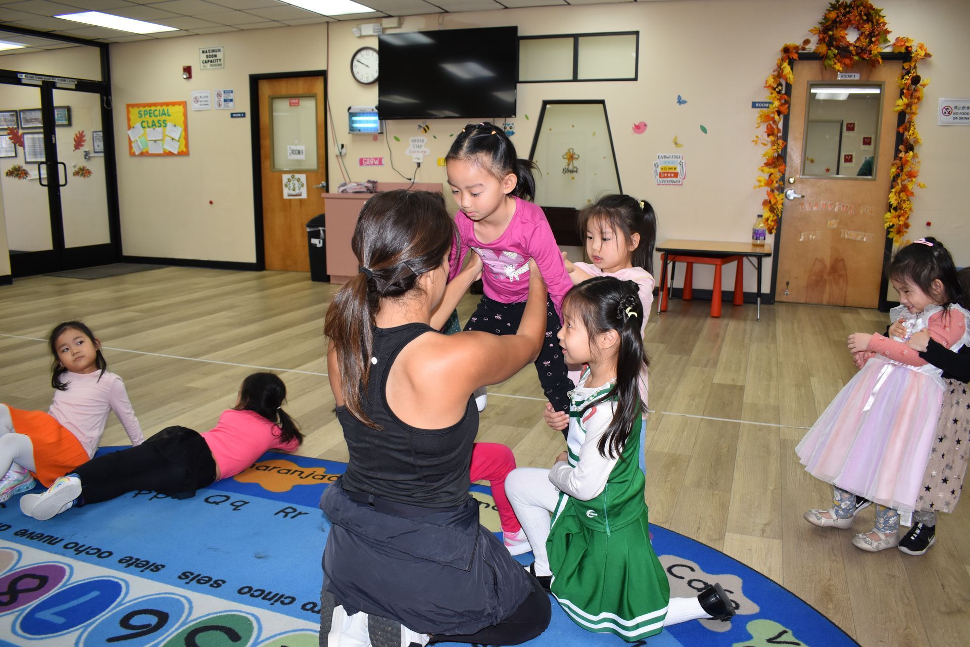 Children and instructor in a playroom. Instructor helps one girl, other girls watch or play.