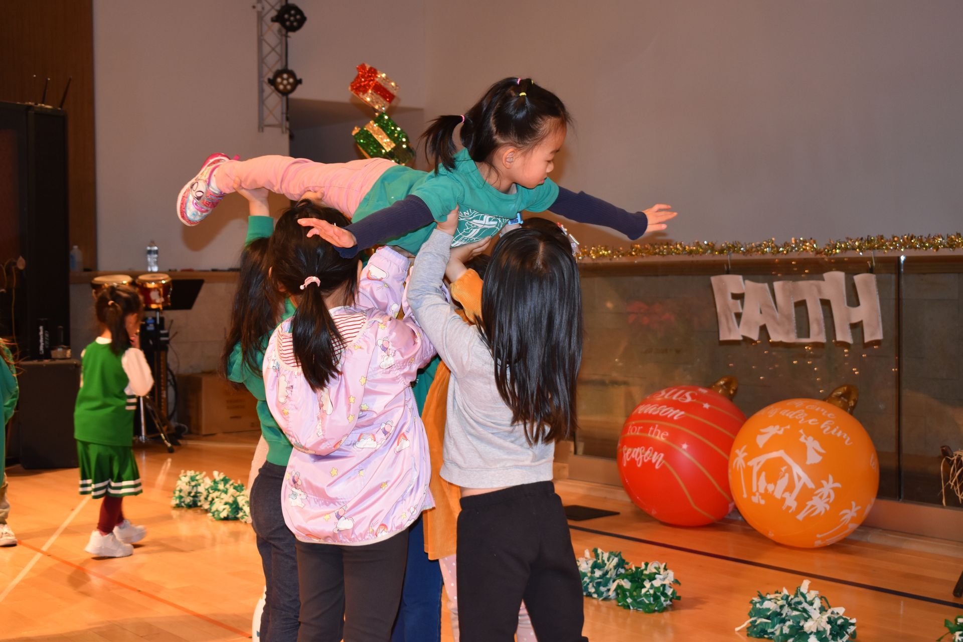 Children holding another child up in the air. Indoors, with 