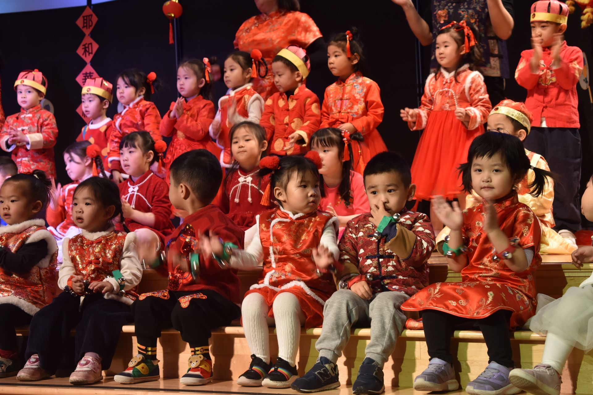 Children in red traditional outfits performing on stage.