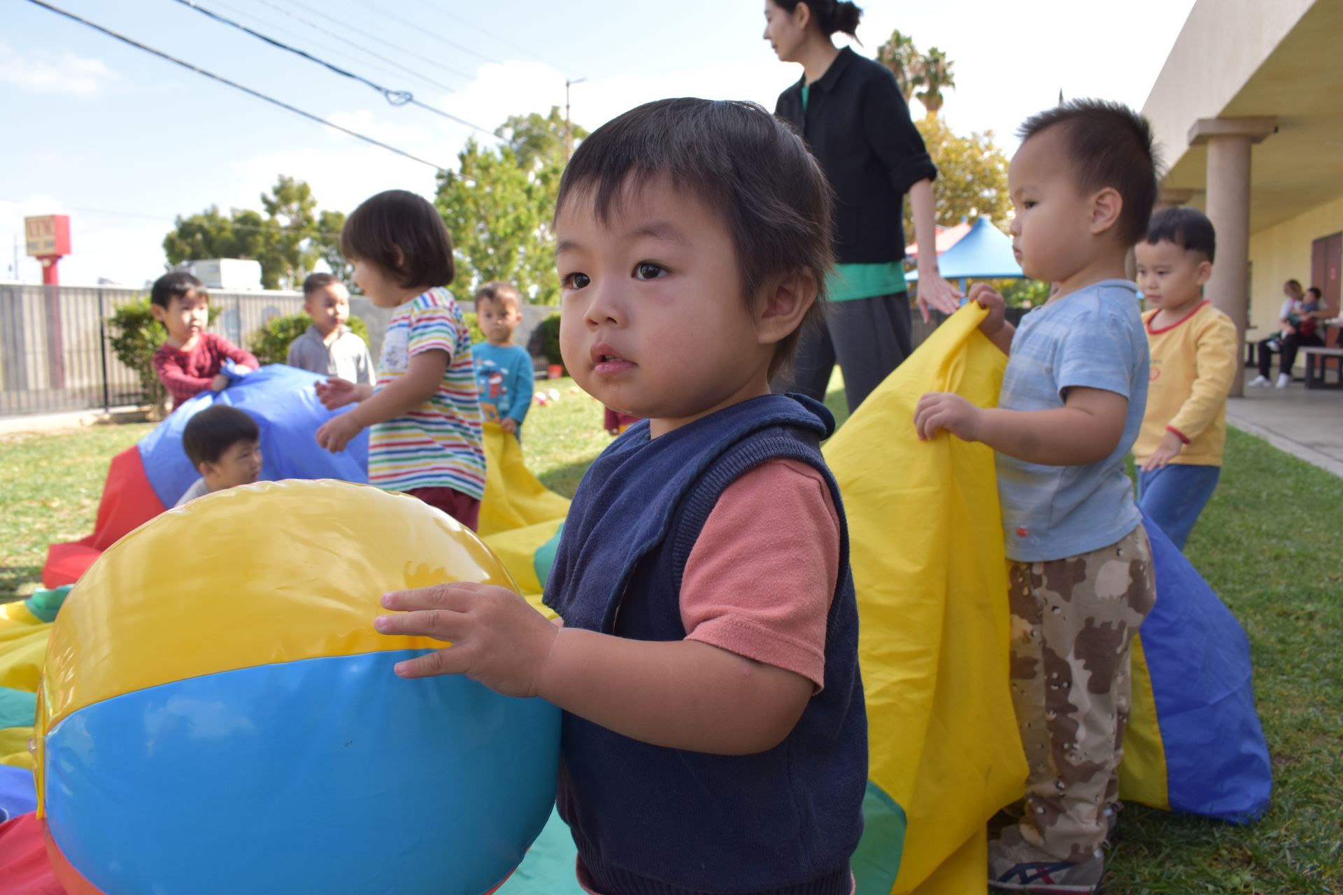 Children playing outside with a colorful parachute and a large ball.